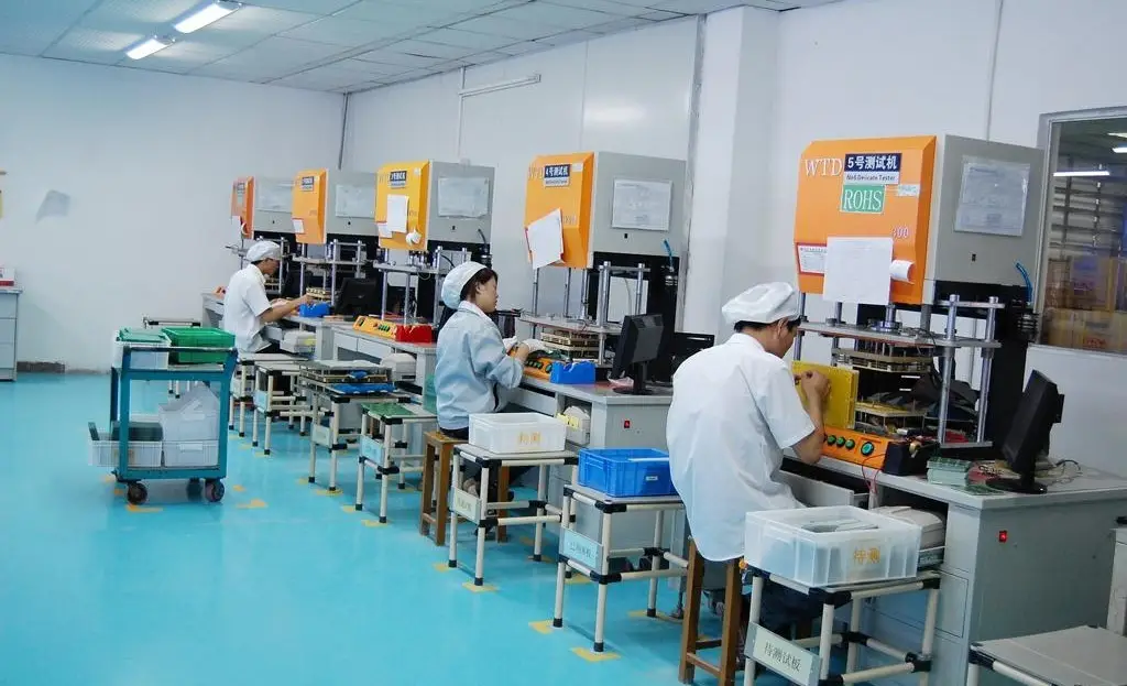 PCB technicians in cleanroom attire conduct testing and assembly on an electronics production line, ensuring quality with specialized equipment.