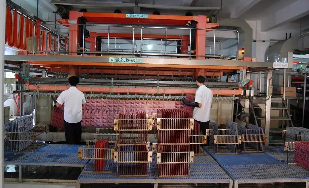 Two technicians oversee an automated PCB electroplating line, loading and unloading panels in a modern electronics manufacturing facility.